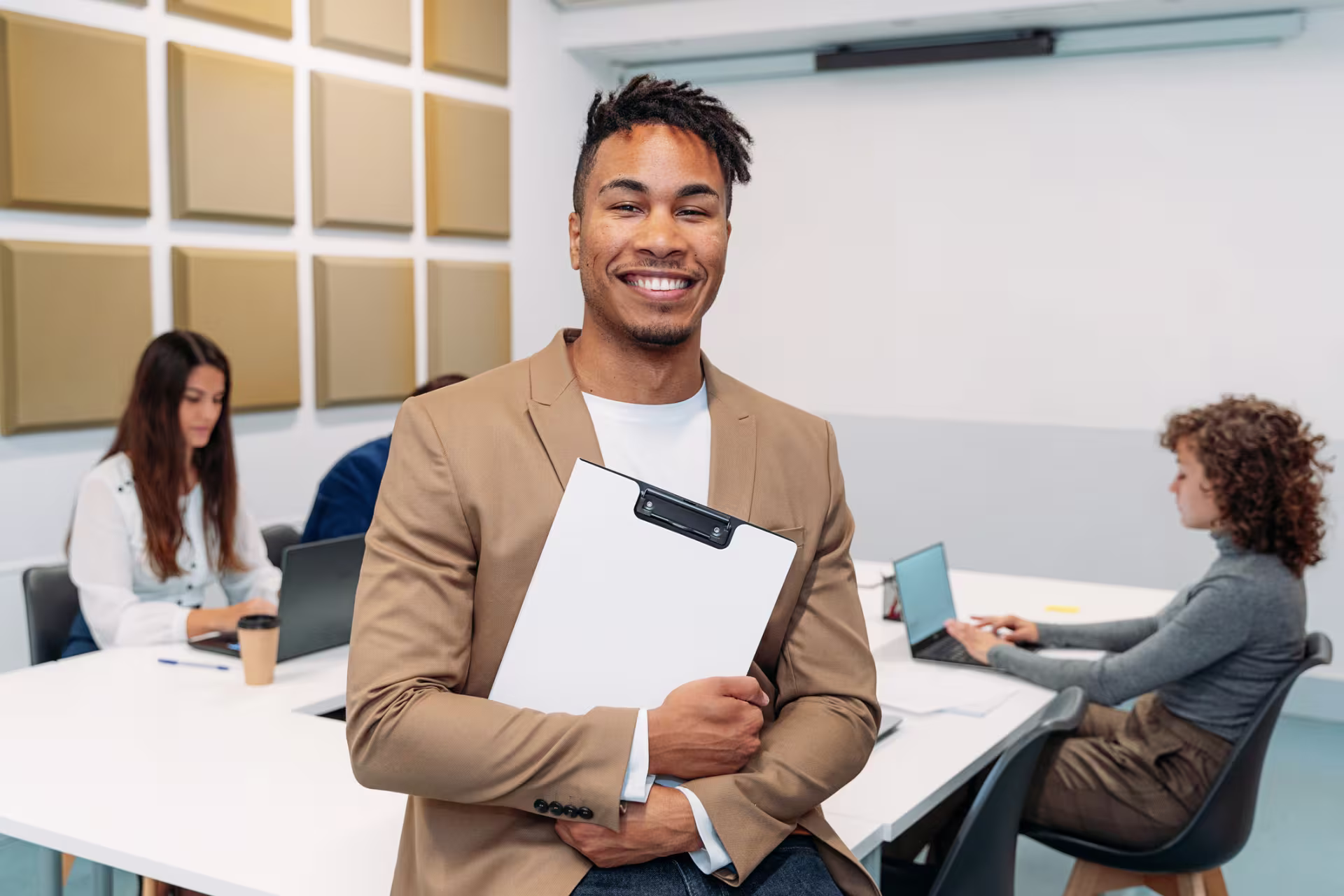 A male business administration student holds a clipboard in a classroom.