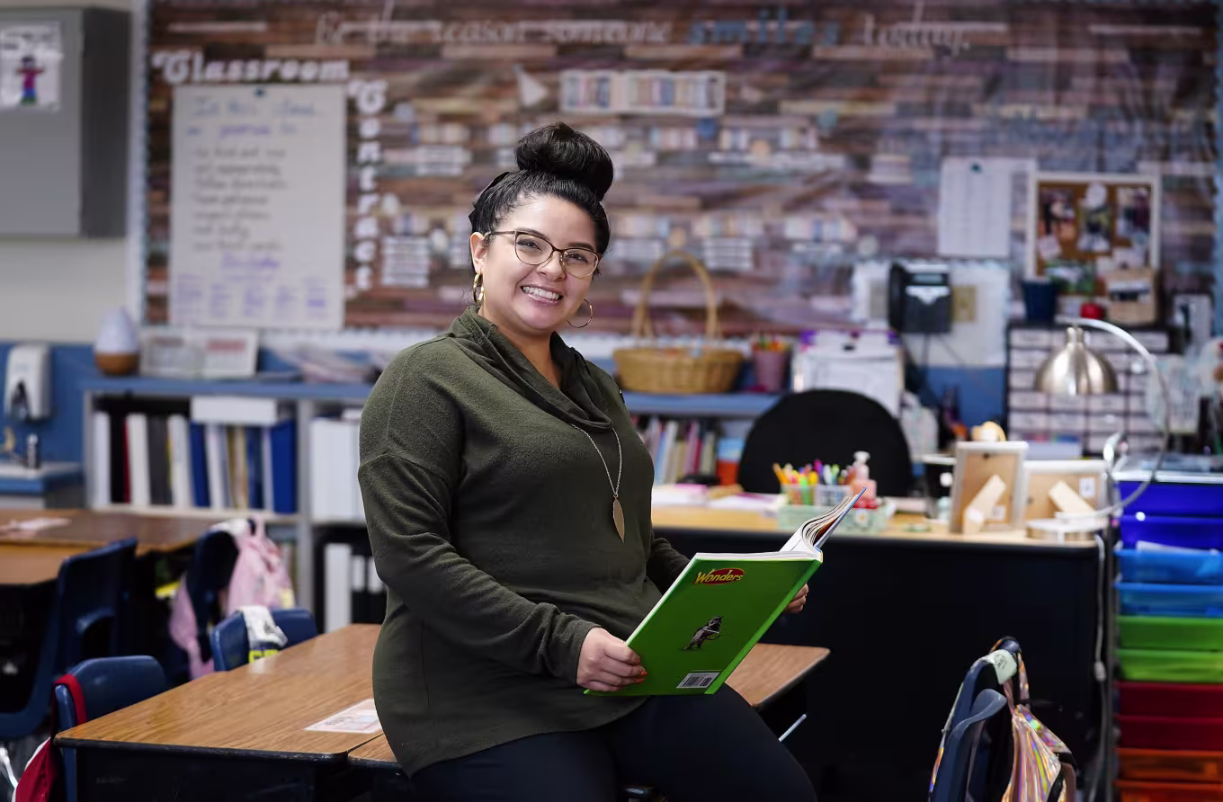 STEM education teacher holding book sitting in classroom