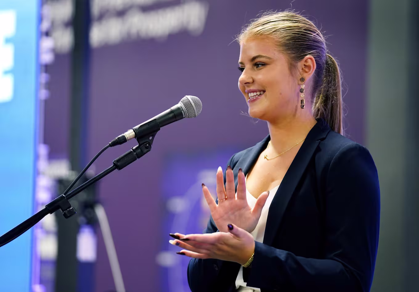 Female entrepreneur clapping while smiling and giving speech