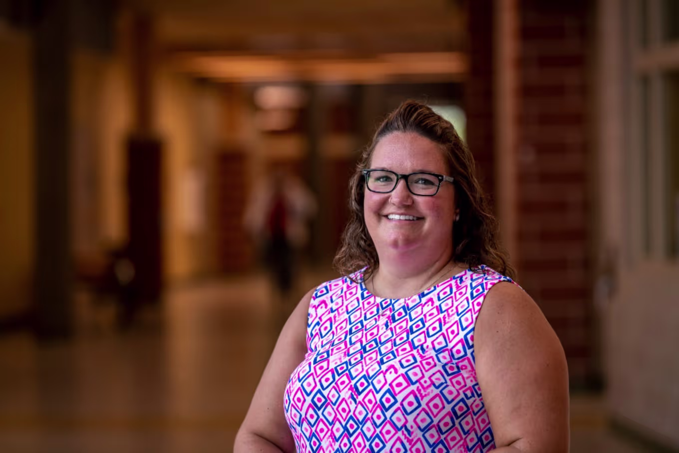 Principal in floral shirt standing in school hallway