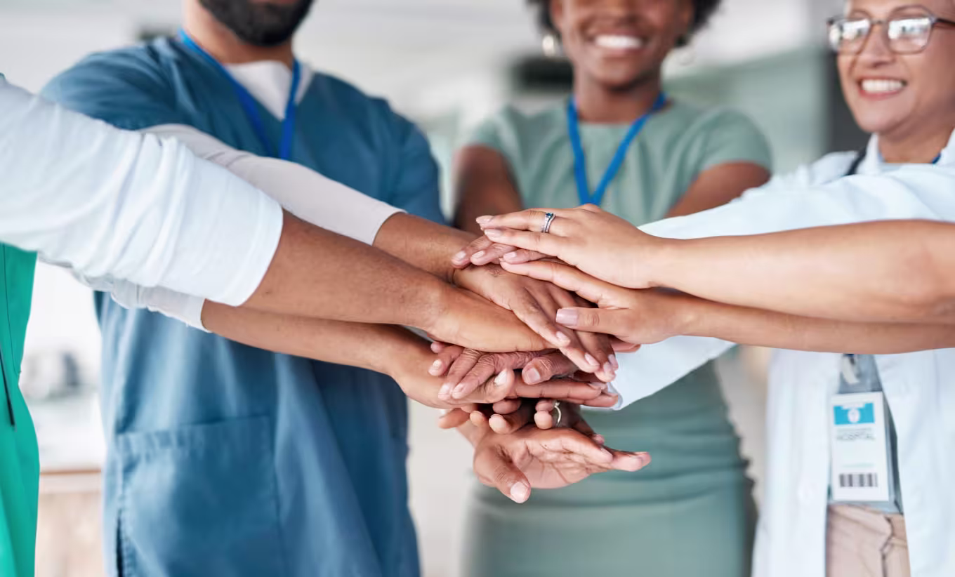 Healthcare professionals joining hands to make a difference in community health and wellness through collaboration in a public health degree program.