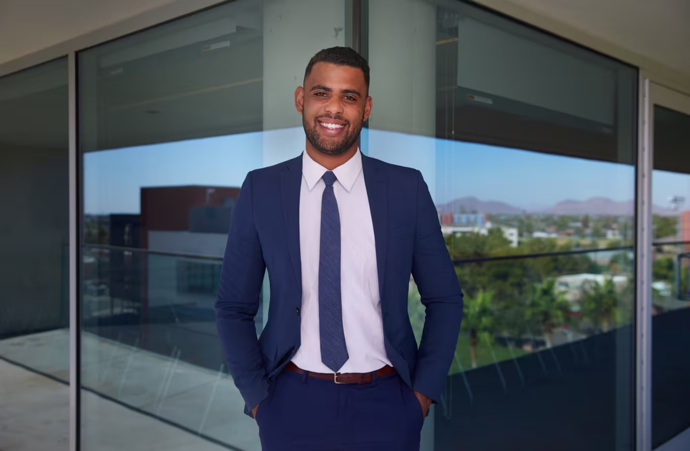Male professional in business attire standing confidently in front of hospital, symbolizing the start of your MBA journey in Health Systems Management.