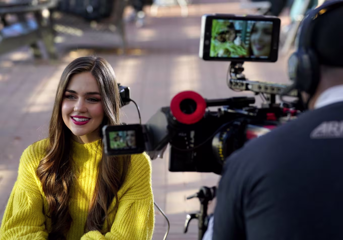 Close up image of cameraman recording female digital film student outside