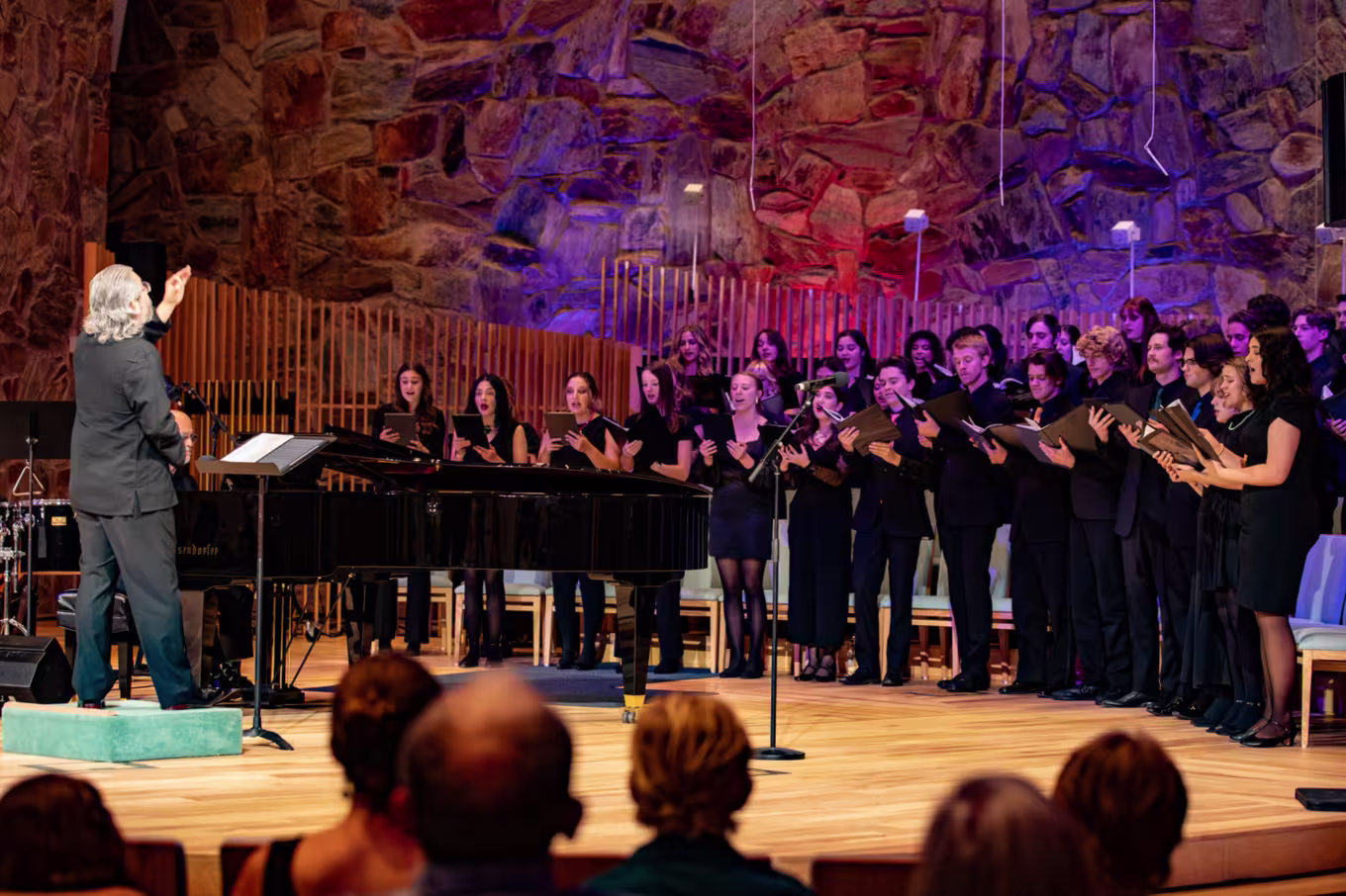 Male conductor leading group of vocal music majors during performance