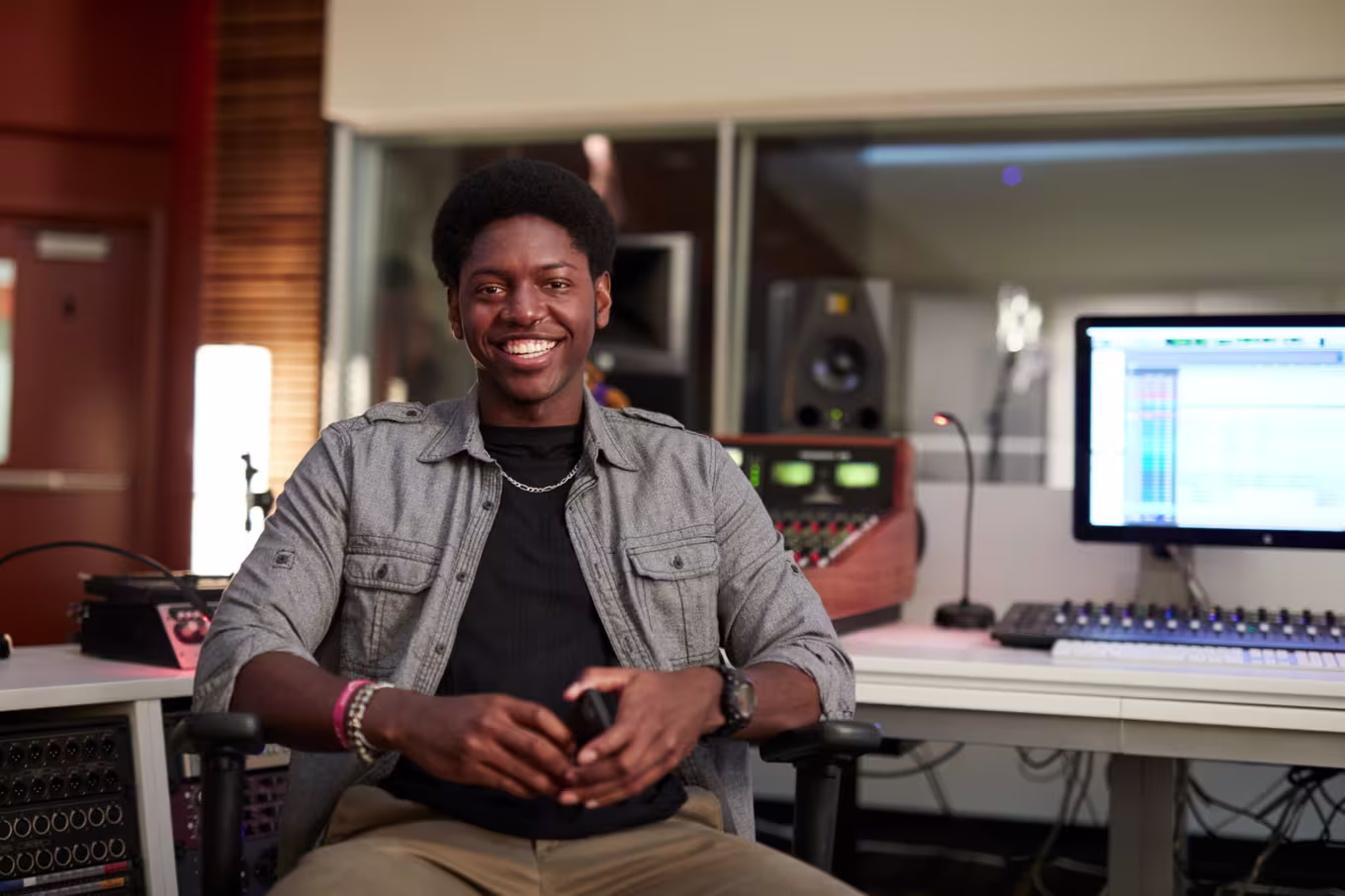 Male music production major smiling while sitting in recording studio