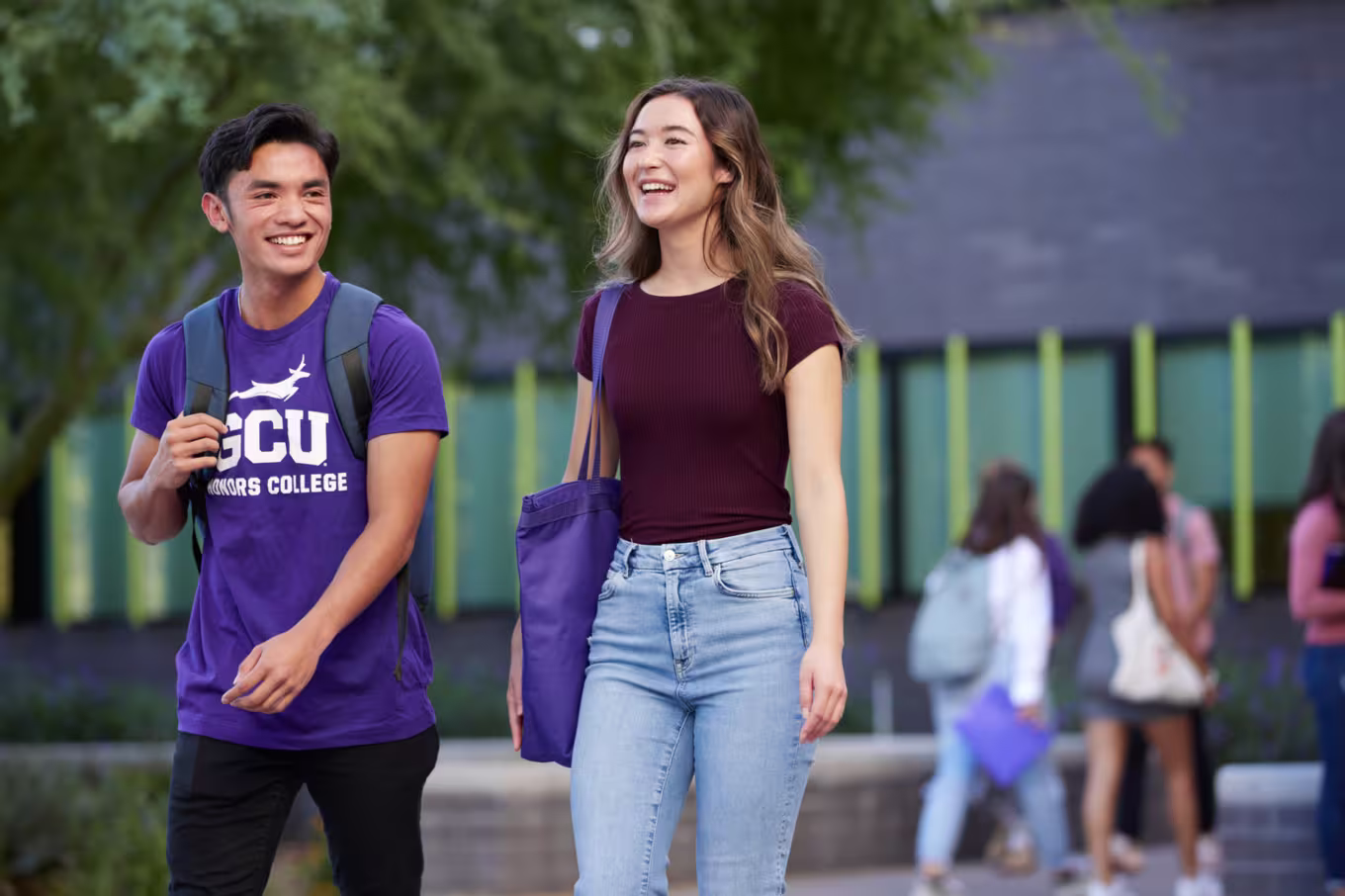 Male and female business majors laughing and walking to class on campus