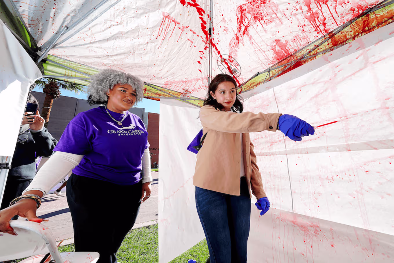 female forensic science students study blood spatter analysis.