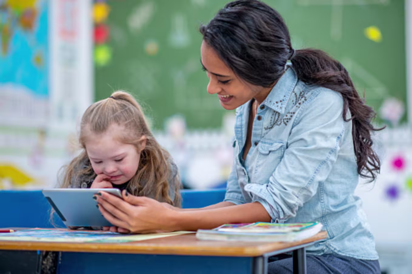 Female teaching assistant working with young student in classroom