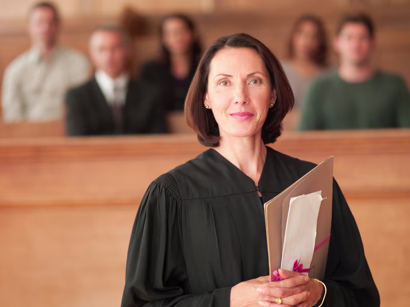 Judge holding a file folder in a courtroom with seated individuals in the background, illustrating a legal proceeding relevant to understanding criminal procedures.