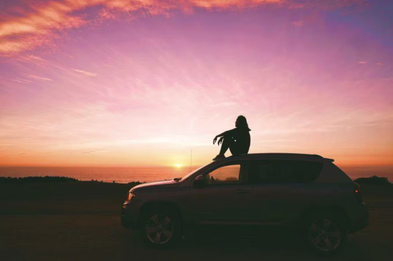 person sitting on his car outside