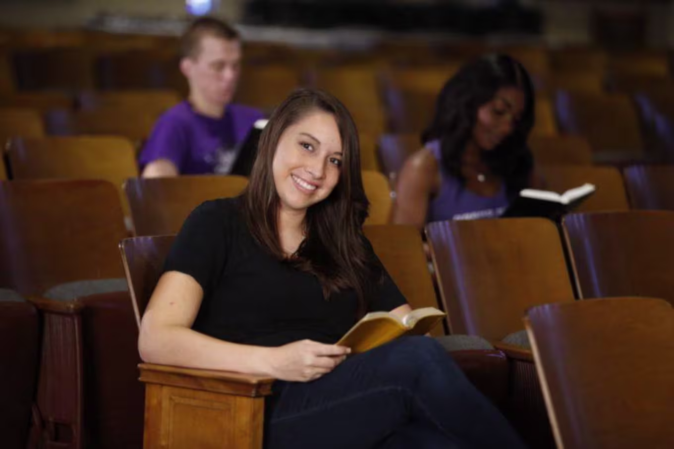 A student sitting in an auditorium reading