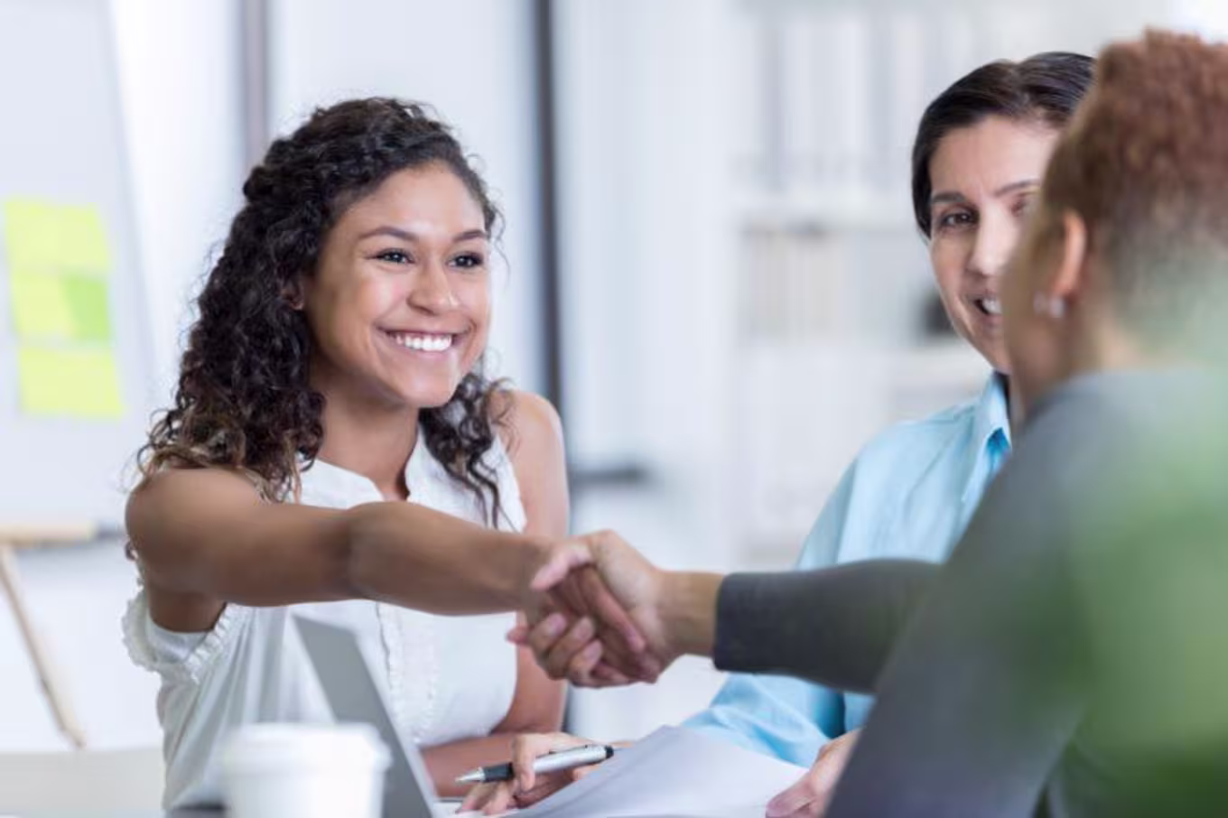Small group of people shake hands and discuss at a table.