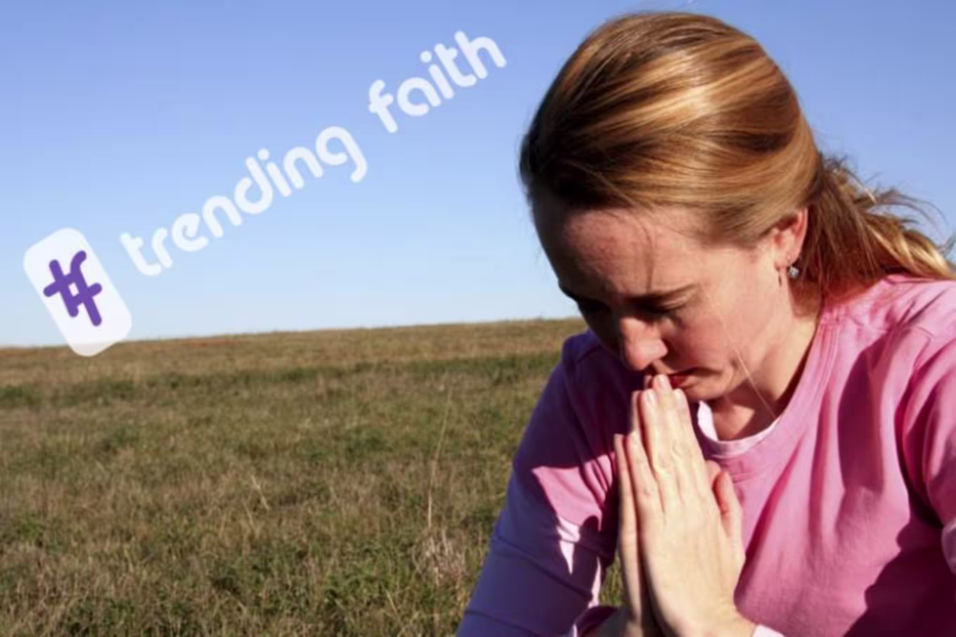 A woman praying in a field under the Trending Faith logo