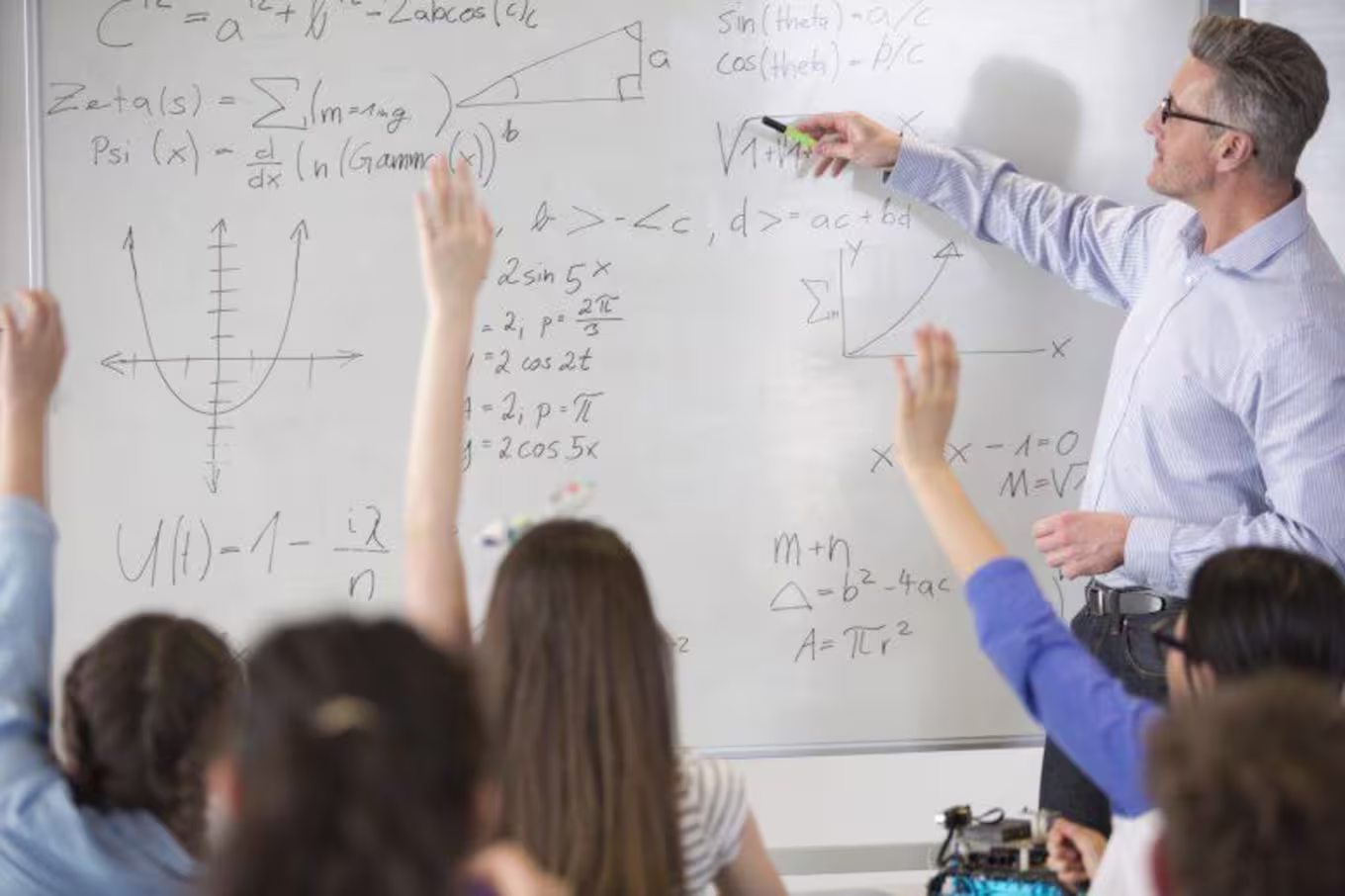 Male teacher leading physics lesson at whiteboard in classroom