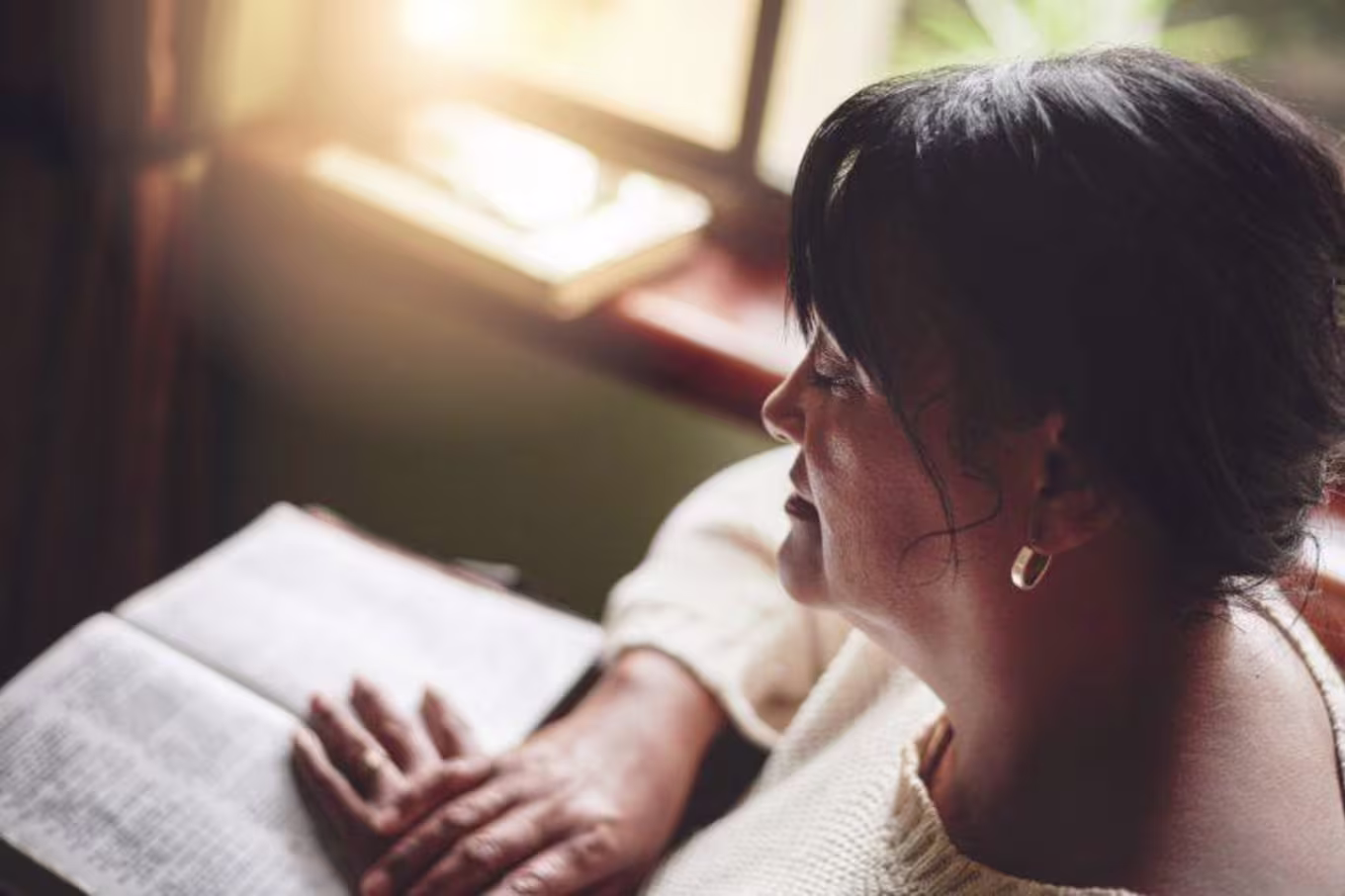 a woman praying over her Bible