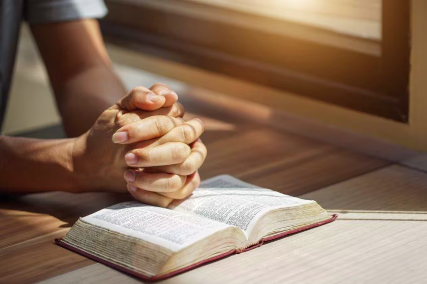 Man praying with his hands over a Bible