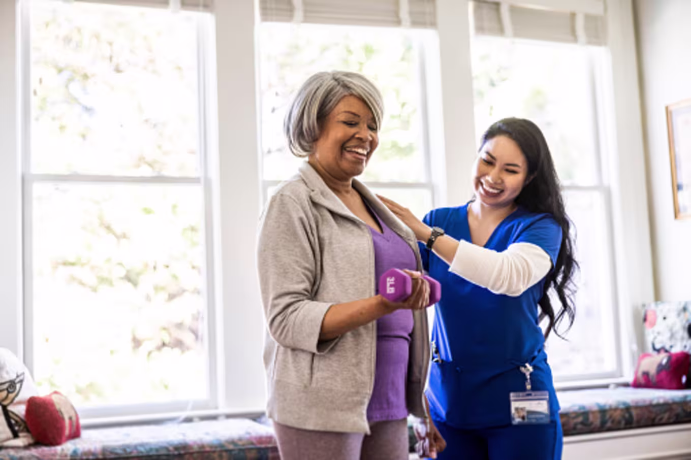 At home nurse helping senior woman with physical therapy at home.