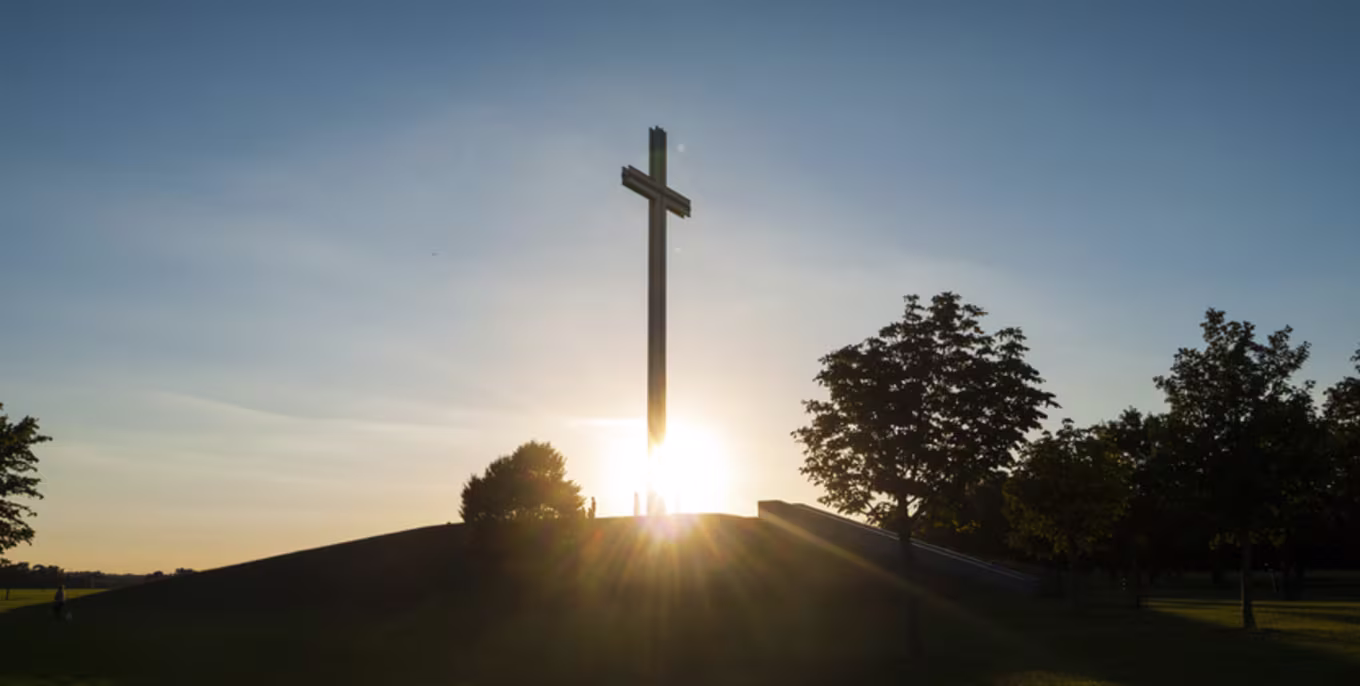 cross on a hill in front of the sun rising