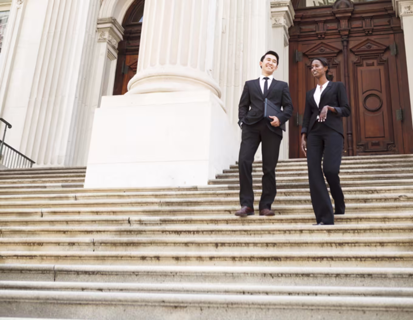 Two politicians on the steps of a courthouse talking together.