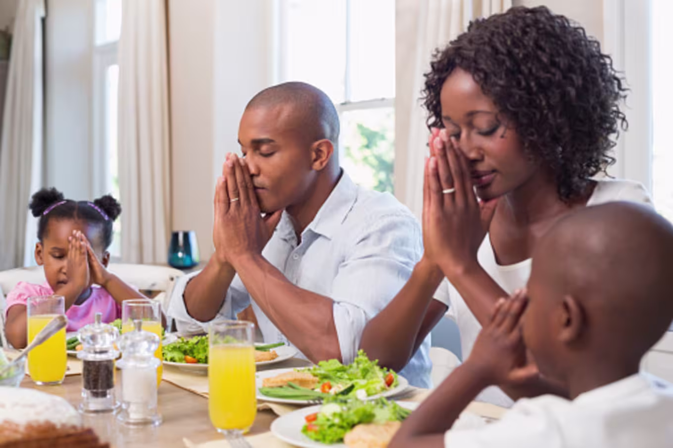 Family praying at the dinner table bearing with one another in love