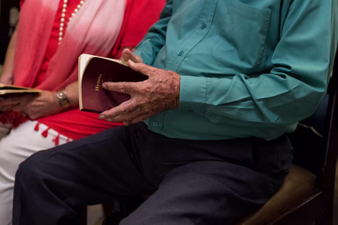 Older couple sitting next to each other open hymnals in a Christian community church