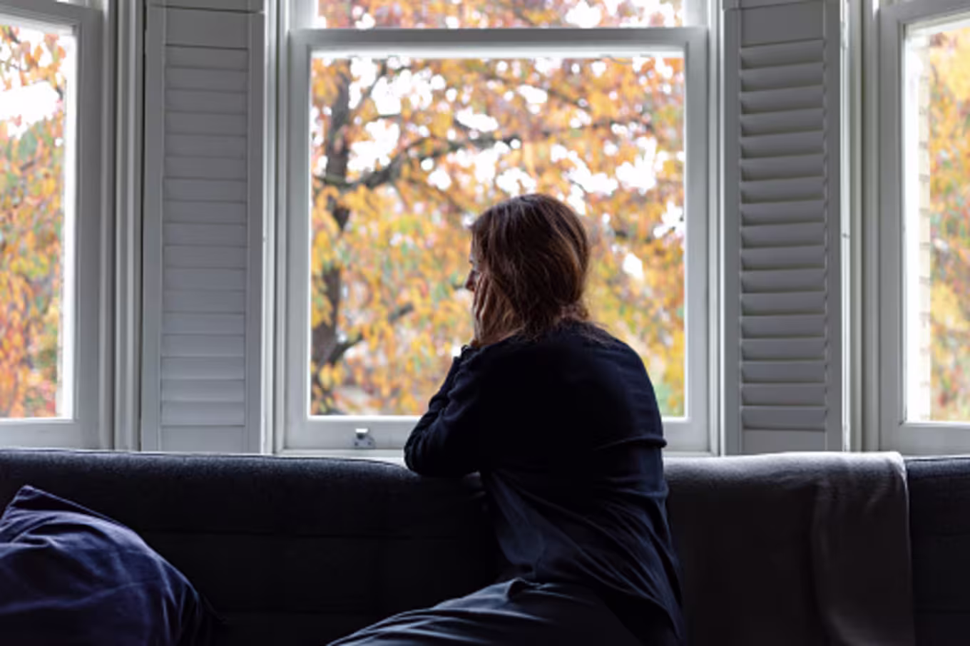 Young woman looking out the window and fighting shame and guilt