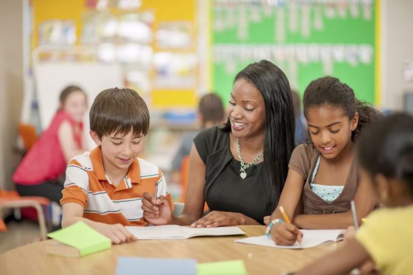 female teacher helping two young students in classroom