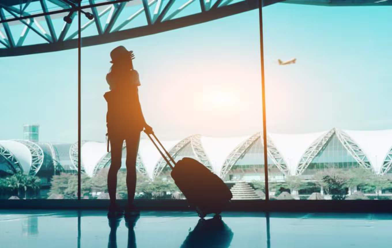 Female student watching a plane take off in an airplane terminal