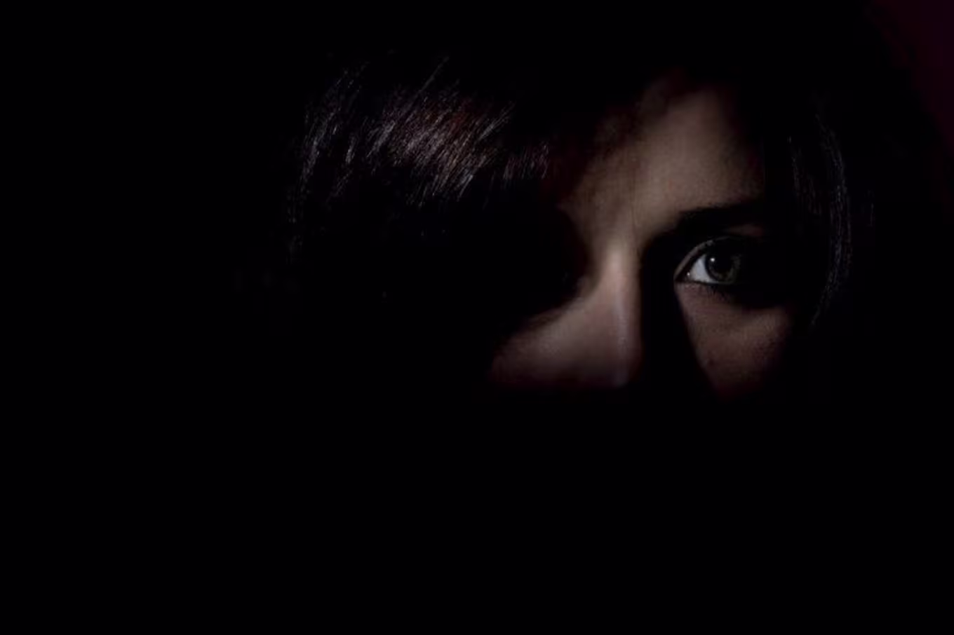 A person's face hiding in the shadows