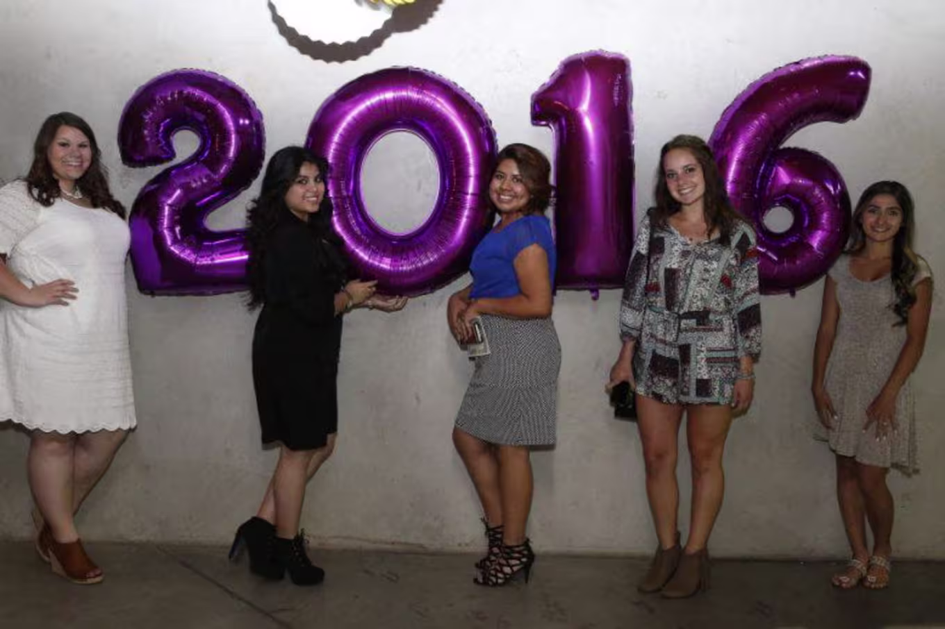 people standing next to 2016 balloons