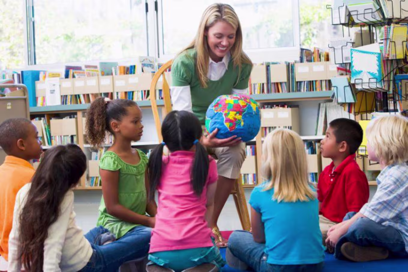 teacher showing a globe to young students