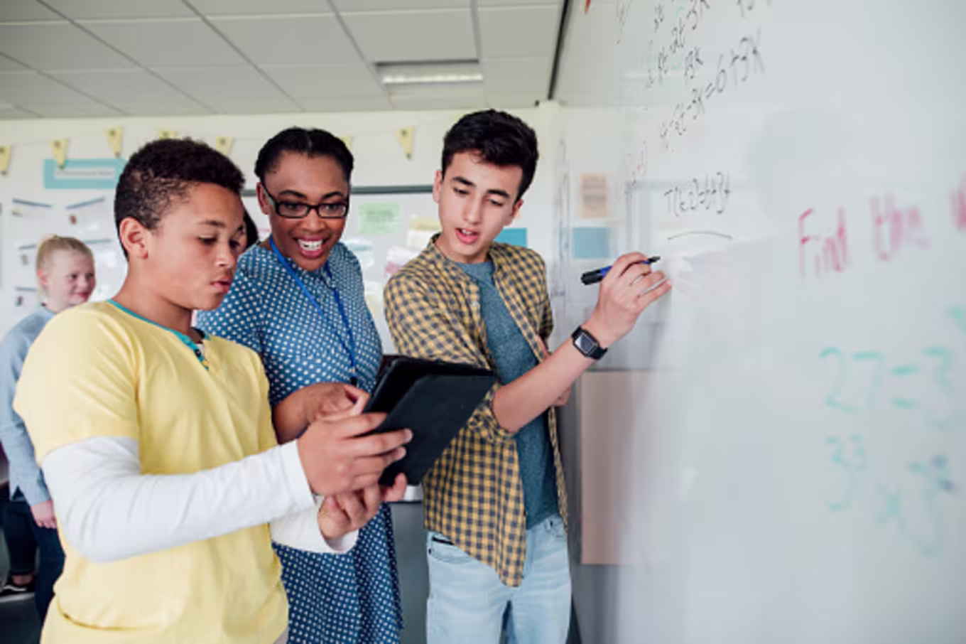 Three students solving a problem at a whiteboard during a multi-discipline lesson