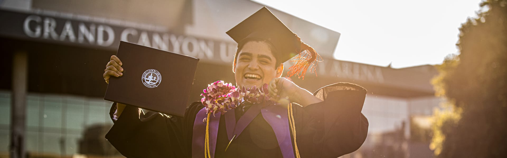 Student jumping and celebrating graduating from GCU wearing ceremony garb.