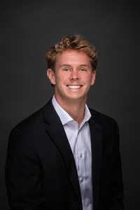 Jake McCreery headshot wearing white shirt and black jacket.