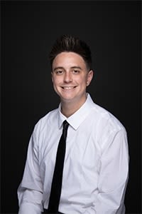 Konnor Bennet headshot wearing white shirt and black tie.