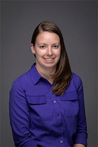 Victoria Woods headshot sitting wearing purple shirt.