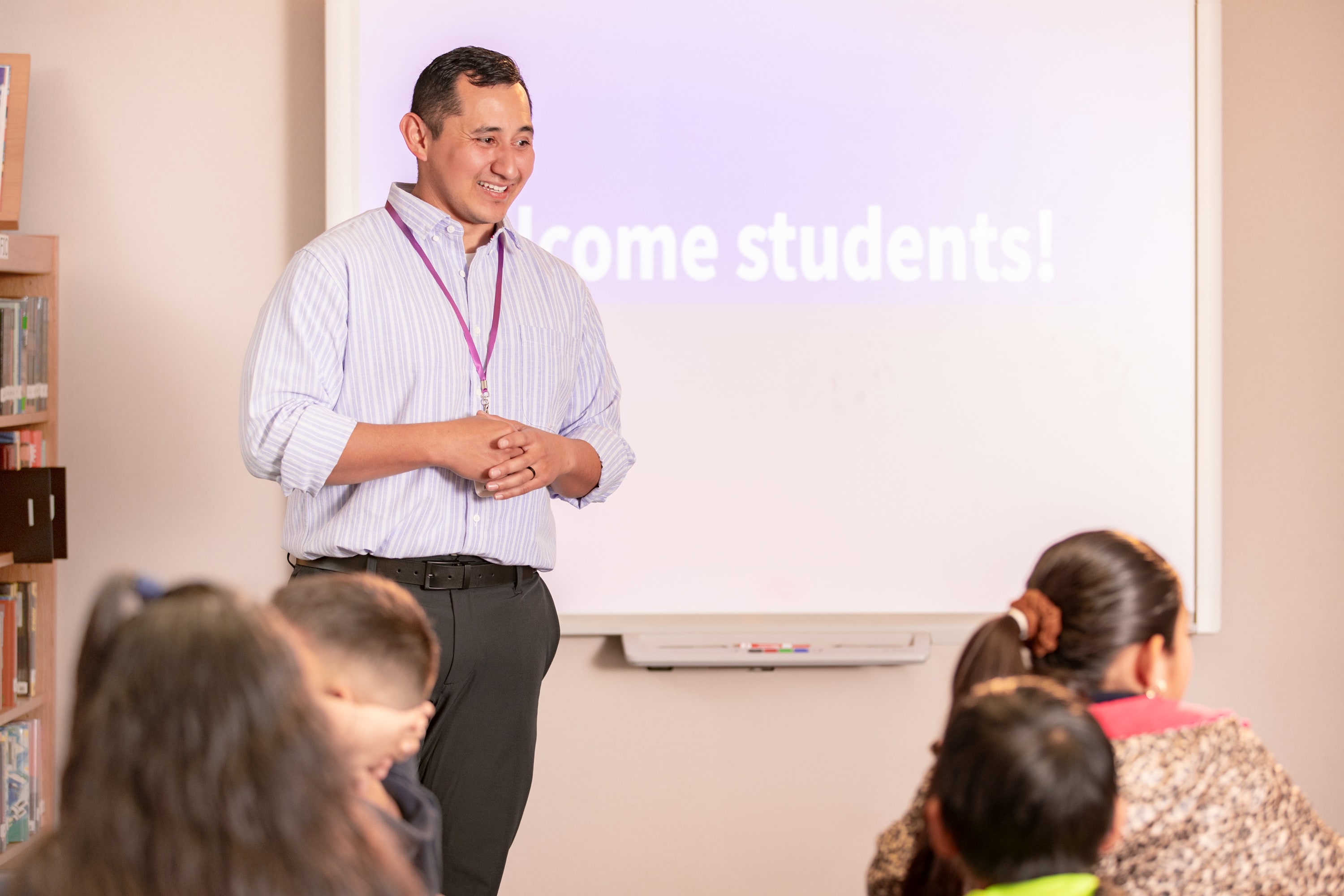 Male education master's degree graduate standing in front of students in classroom