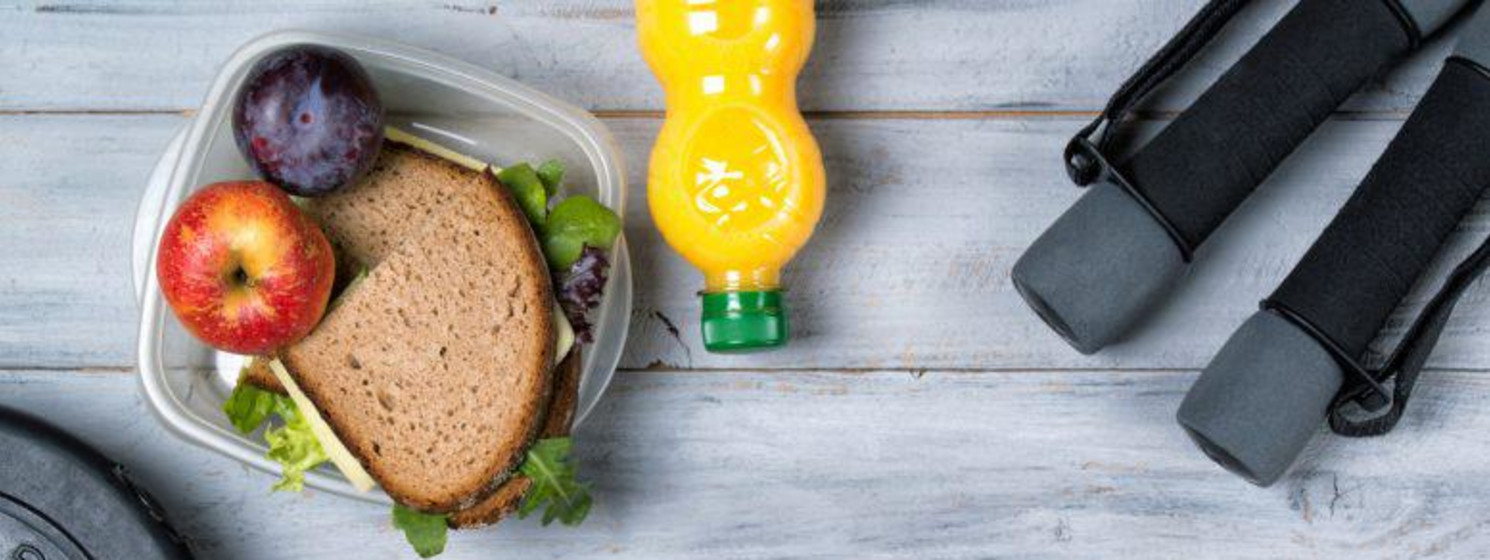 Healthy drink and food in Tupperware next to weights jumprope handles and tennis shoes