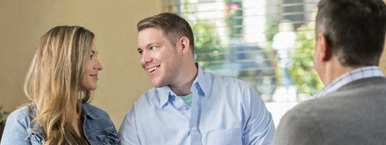 Marriage therapist with a cup of coffee observes couple looking lovingly at each other