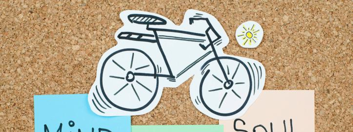 Bicycle illustration and sticky notes with Mind Body Soul are on cork board