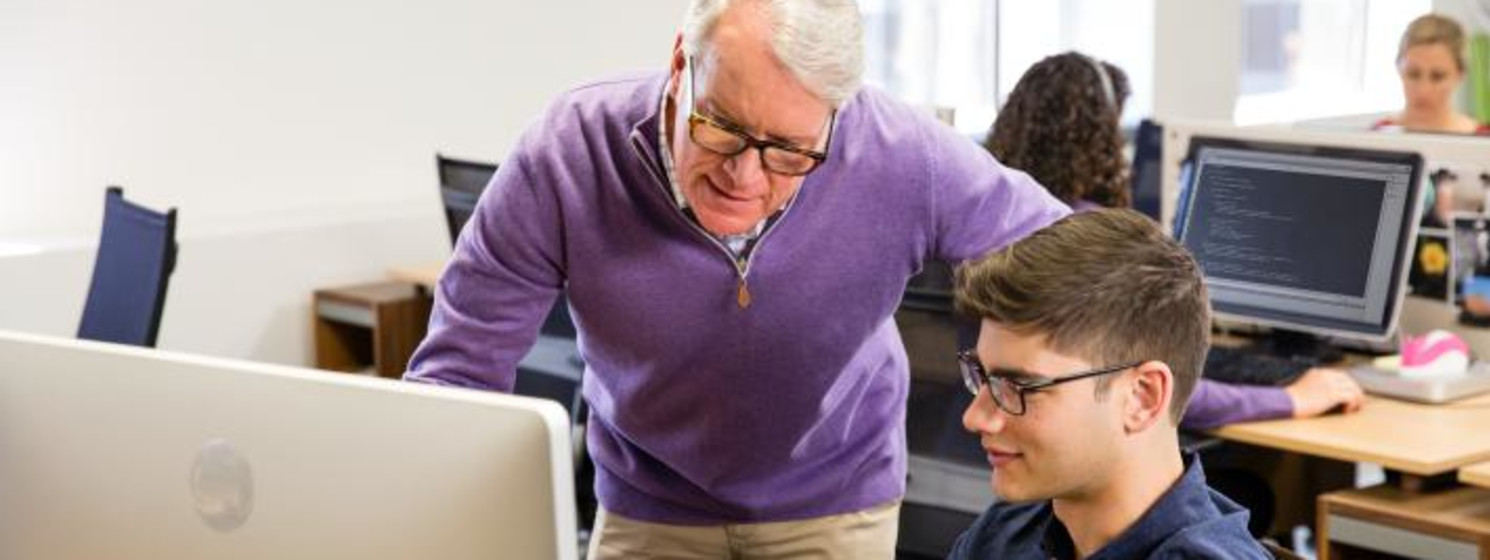 Programmer working at a computer with his professor