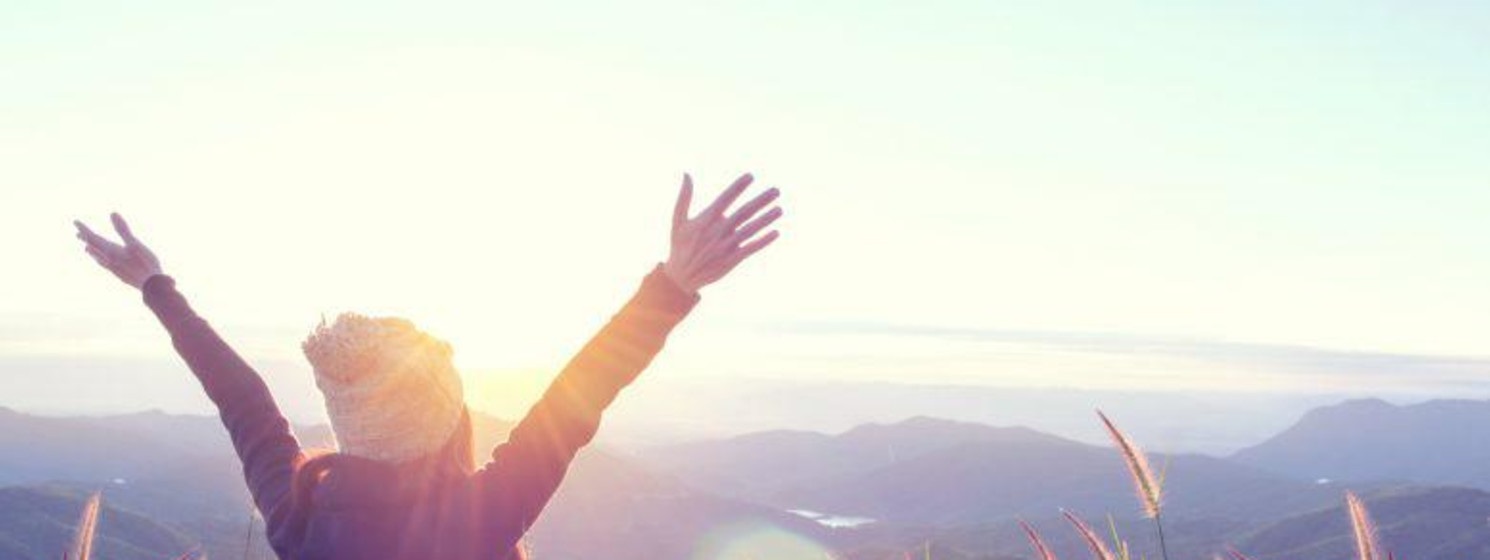 woman with arms raised in an open field