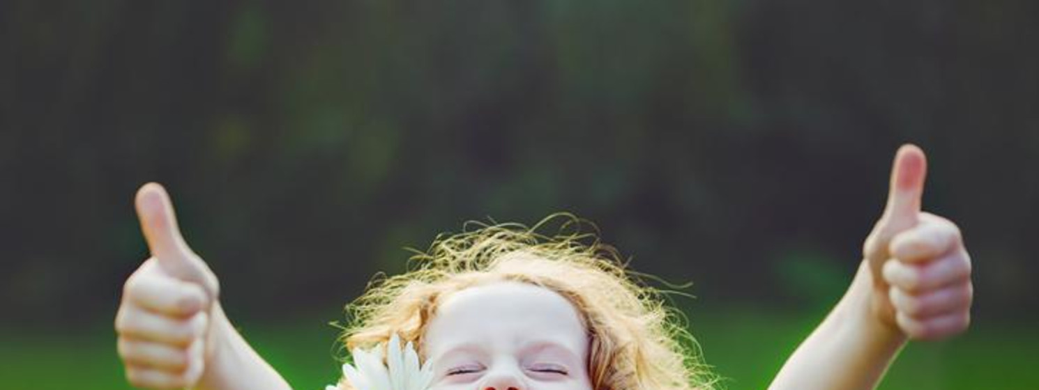 Girl in a field holding two thumbs up