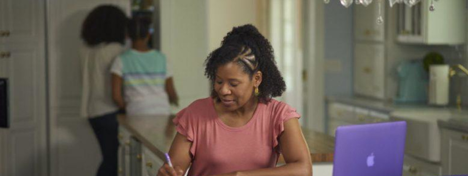 A woman taking notes at her kitchen table
