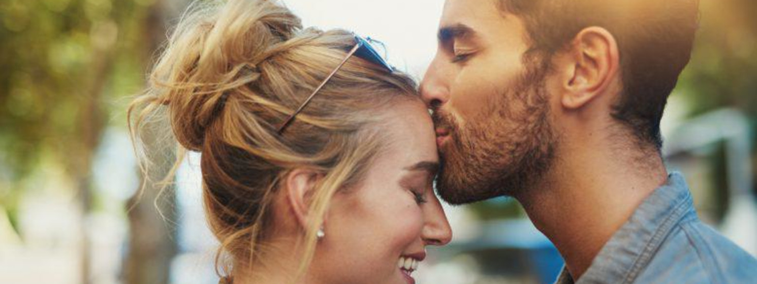 A man kissing a woman on her forehead