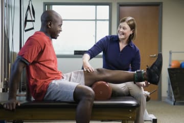 physical therapist working with a patient beside exercise equipment