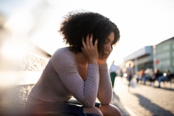 Young woman sitting alone in a sad state of mind.