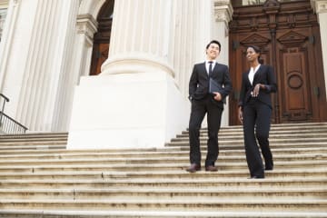 Two politicians on the steps of a courthouse talking together.