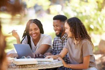 Students, friends and group studying with laptop at park outdoors. Education scholarship, learning teamwork and happy people, black man and women with computer for research at university or college. - stock photo