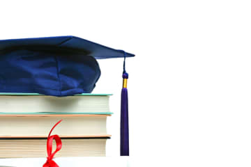 graduation cap on top of books and a diploma